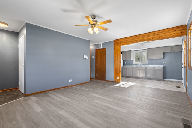 unfurnished living room featuring light hardwood / wood-style floors, ceiling fan, crown molding, and sink