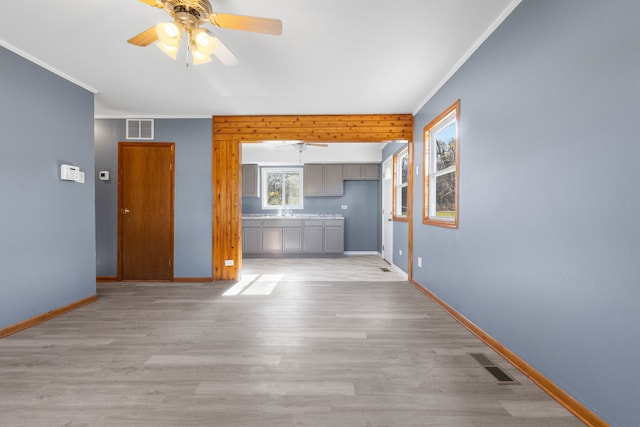 unfurnished living room with crown molding, ceiling fan, and light wood-type flooring