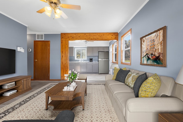 living room with crown molding, sink, and ceiling fan