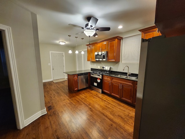 kitchen featuring kitchen peninsula, stainless steel appliances, sink, dark hardwood / wood-style floors, and hanging light fixtures