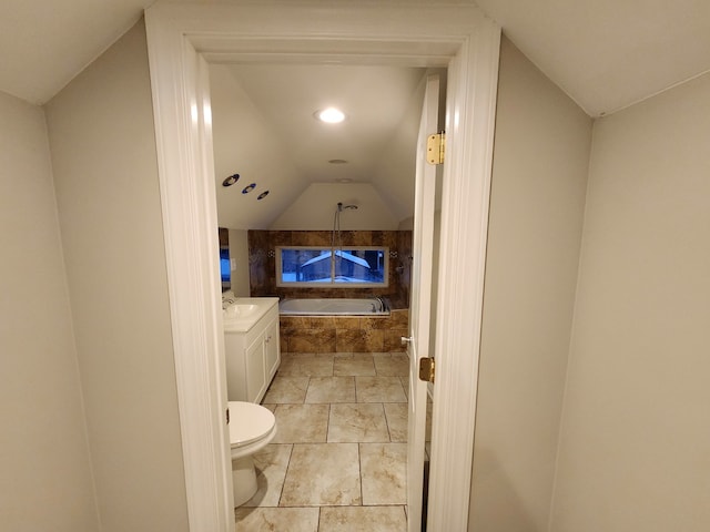 bathroom with toilet, vanity, vaulted ceiling, and tiled tub