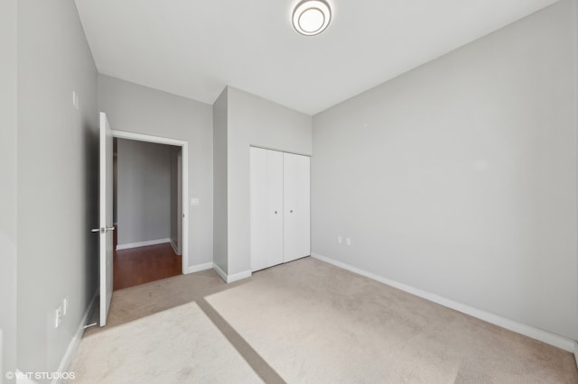 unfurnished bedroom featuring light carpet and a closet