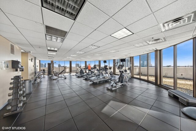 gym with a drop ceiling, expansive windows, and plenty of natural light