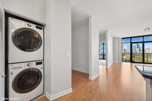 laundry area with stacked washing maching and dryer and light hardwood / wood-style floors