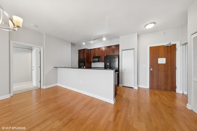 kitchen featuring kitchen peninsula, light hardwood / wood-style floors, and black appliances