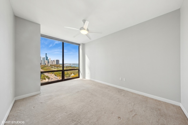 carpeted spare room featuring floor to ceiling windows and ceiling fan