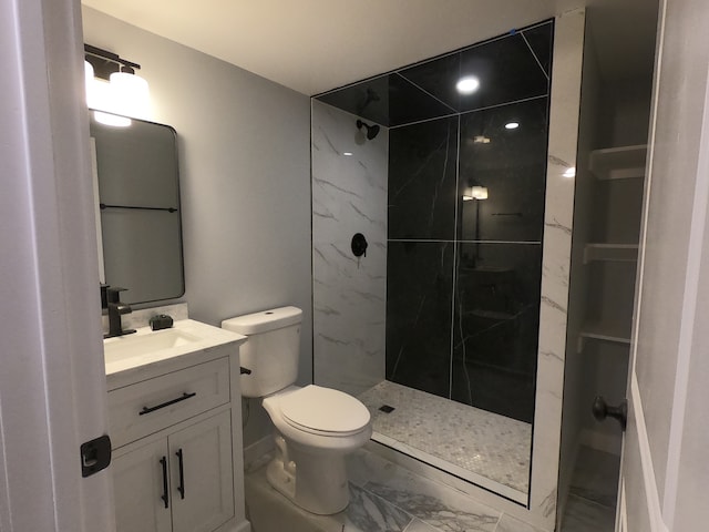 bathroom featuring toilet, vanity, and tiled shower