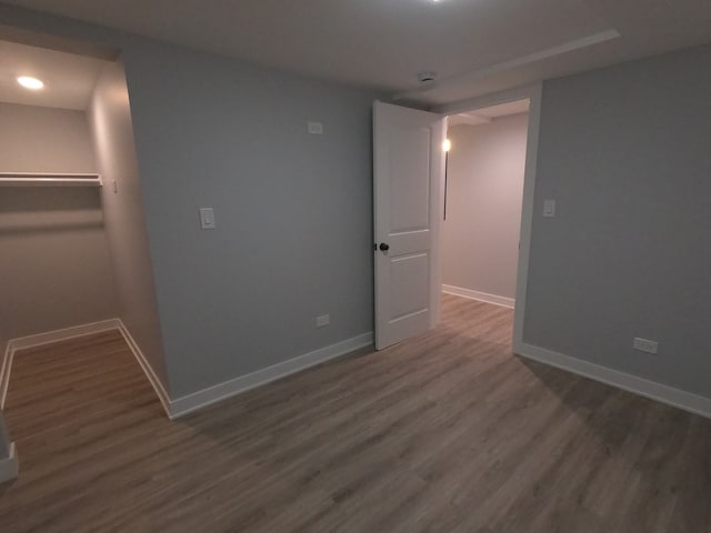 unfurnished bedroom with a walk in closet, dark hardwood / wood-style floors, and a closet