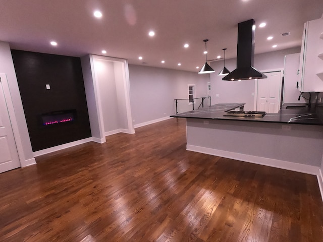 kitchen featuring kitchen peninsula, dark hardwood / wood-style flooring, island range hood, sink, and decorative light fixtures