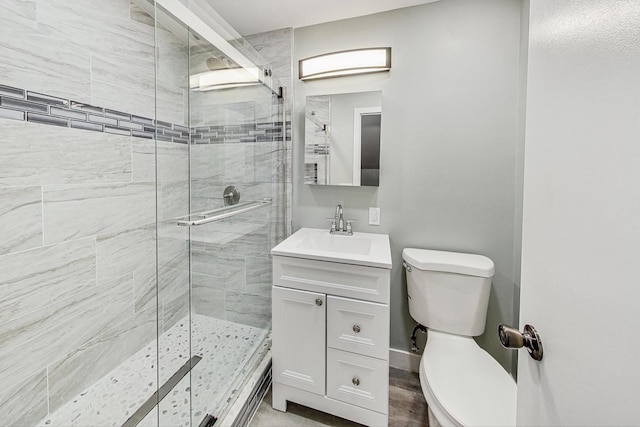 bathroom featuring vanity, toilet, and a shower with shower door