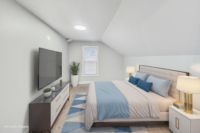 bedroom with light hardwood / wood-style floors and lofted ceiling