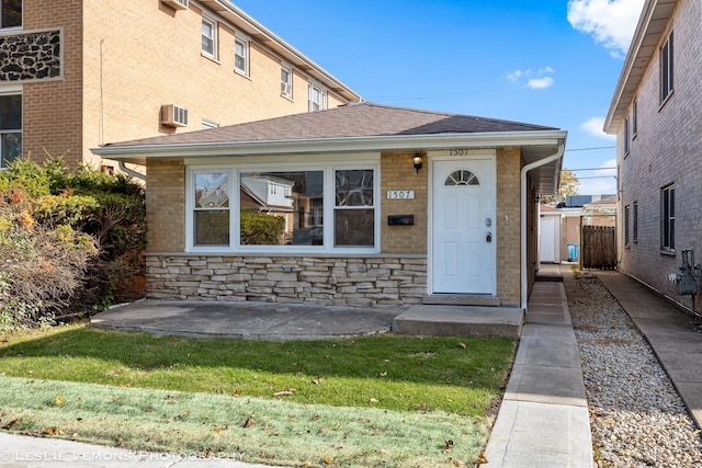 view of front of property featuring a wall mounted air conditioner and a front lawn