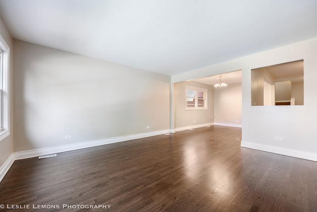 spare room featuring dark hardwood / wood-style flooring and a notable chandelier