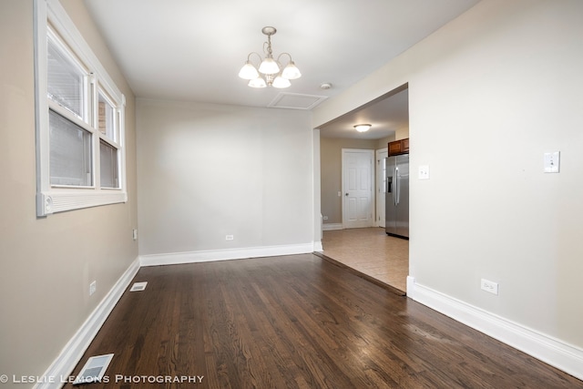 unfurnished room with dark wood-type flooring and an inviting chandelier