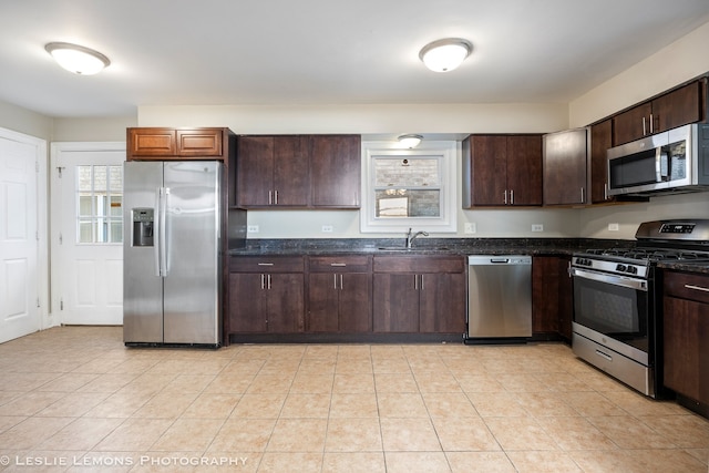 kitchen with dark brown cabinets, dark stone countertops, sink, and appliances with stainless steel finishes