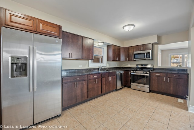 kitchen featuring appliances with stainless steel finishes, sink, dark brown cabinets, and light tile patterned flooring