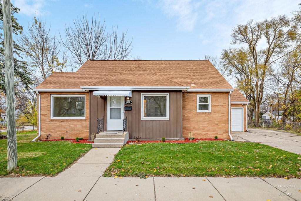 bungalow-style house with a garage and a front lawn