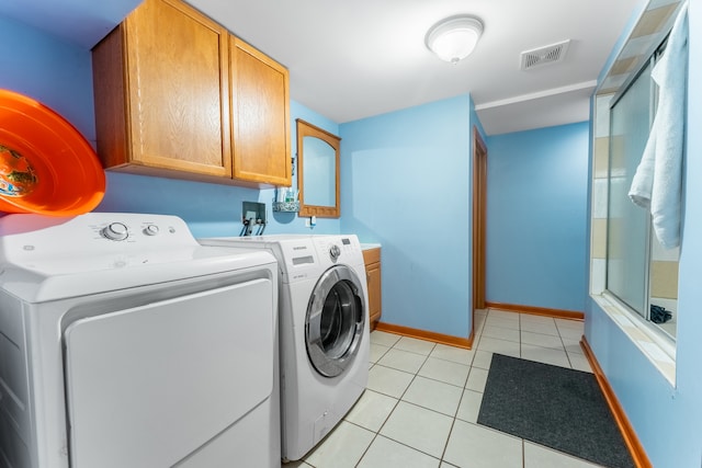 clothes washing area featuring cabinets, separate washer and dryer, and light tile patterned floors