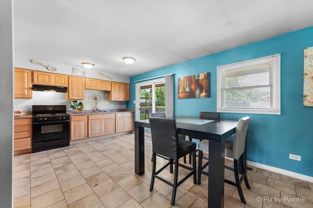 kitchen featuring light brown cabinetry, black range with gas cooktop, stone countertops, and sink