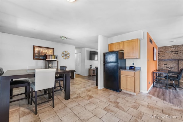 kitchen featuring black refrigerator and light brown cabinetry