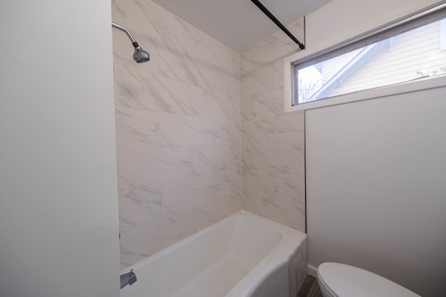 bathroom with toilet and tiled shower / bath