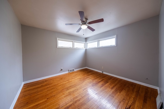 empty room with ceiling fan, wood-type flooring, and a wealth of natural light