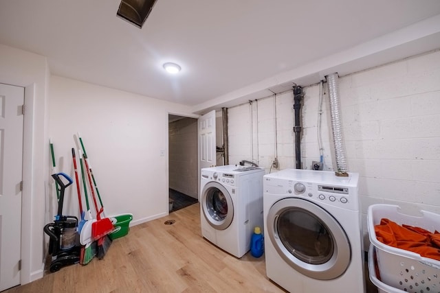 laundry area with light hardwood / wood-style floors and washing machine and clothes dryer