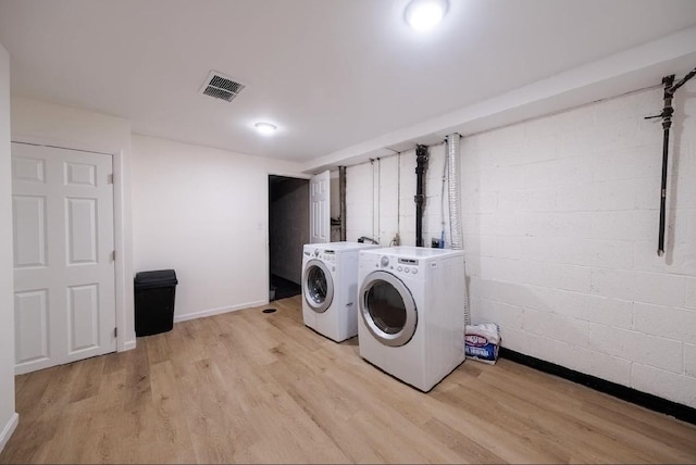 clothes washing area featuring washing machine and dryer and light wood-type flooring