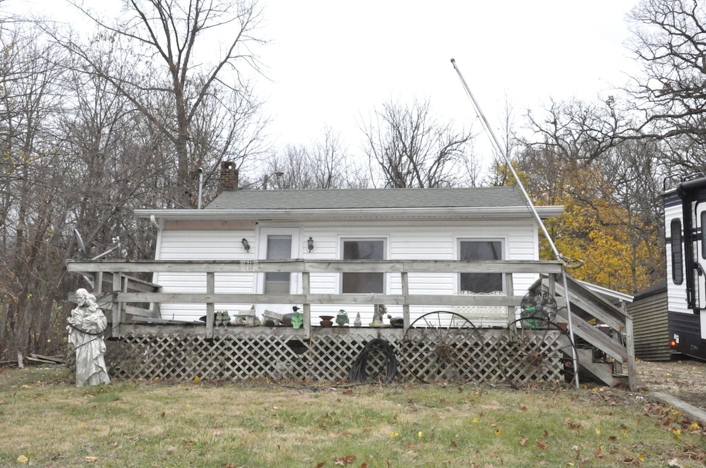 rear view of house featuring a deck and a lawn