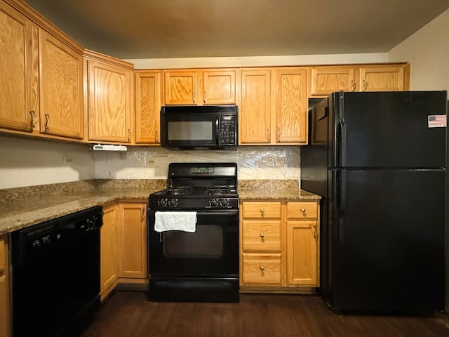 kitchen with light stone countertops, dark hardwood / wood-style floors, tasteful backsplash, and black appliances