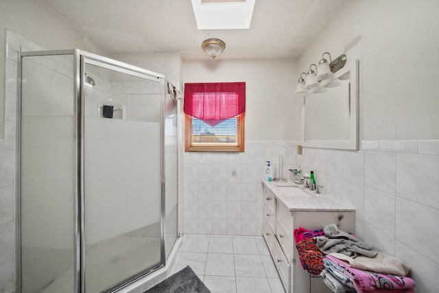 bathroom with vanity, a skylight, an enclosed shower, and tile walls