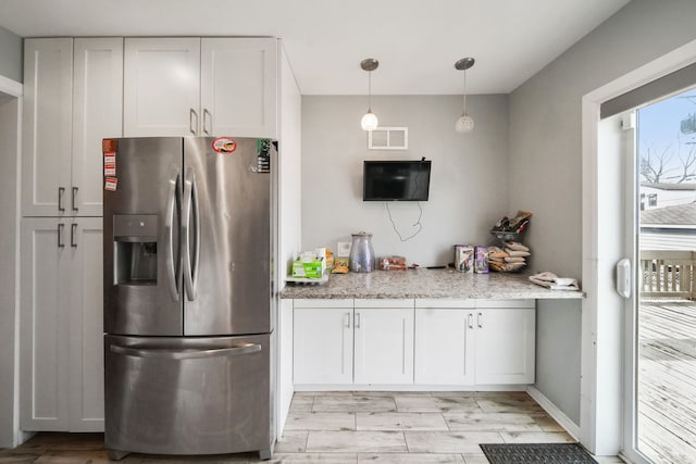 kitchen with pendant lighting, stainless steel refrigerator with ice dispenser, light hardwood / wood-style floors, light stone counters, and white cabinetry