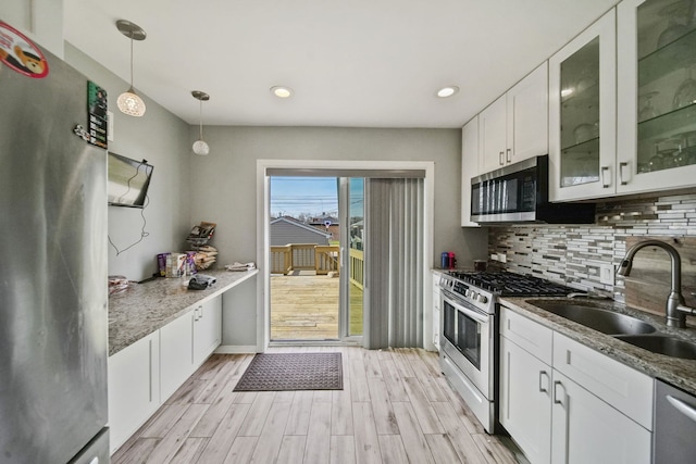 kitchen with white cabinetry, stainless steel appliances, stone countertops, and decorative light fixtures