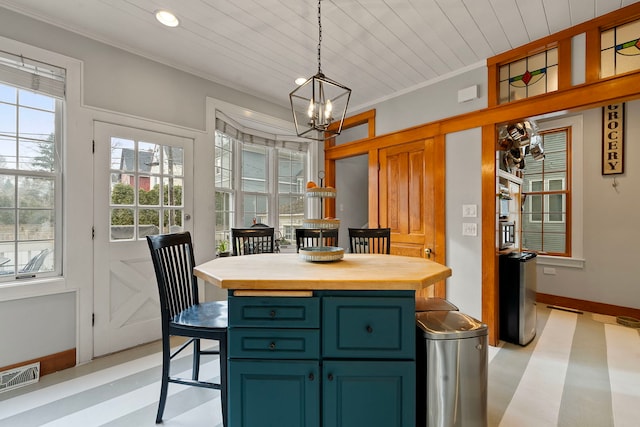 kitchen with blue cabinetry, ornamental molding, decorative light fixtures, and an inviting chandelier