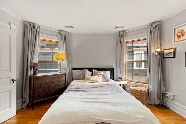 bedroom with multiple windows, crown molding, and hardwood / wood-style floors