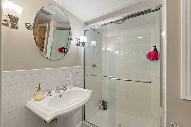 bathroom featuring a shower with shower door, sink, and tile walls