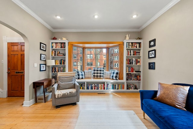 sitting room with ornamental molding and light hardwood / wood-style flooring