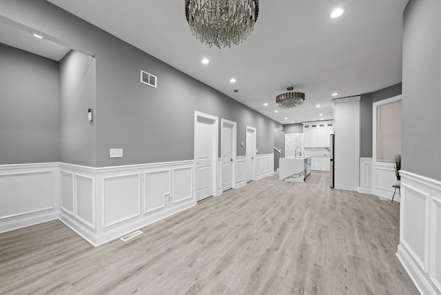 hall featuring a chandelier, light hardwood / wood-style floors, and sink