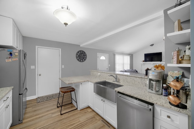 kitchen featuring white cabinets, sink, vaulted ceiling, light hardwood / wood-style flooring, and stainless steel appliances