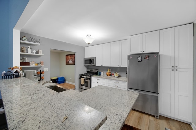 kitchen featuring sink, light hardwood / wood-style floors, light stone counters, white cabinetry, and stainless steel appliances