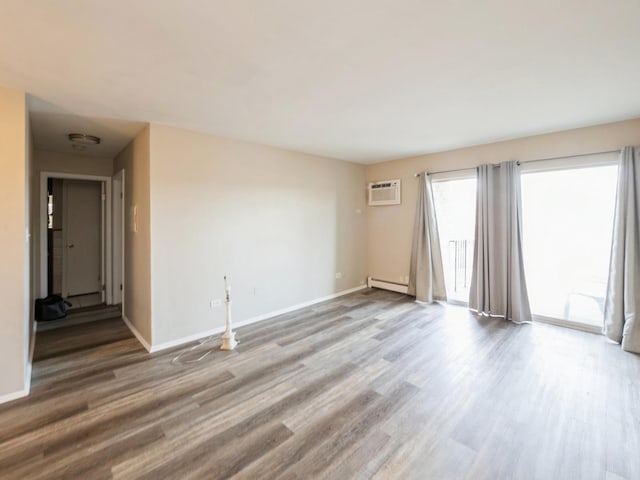 empty room featuring wood-type flooring, a wall mounted AC, and a baseboard radiator