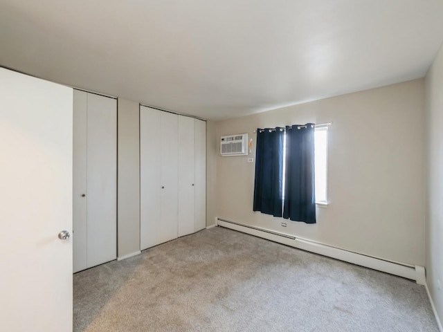 unfurnished bedroom with light colored carpet, baseboard heating, a wall mounted AC, and two closets