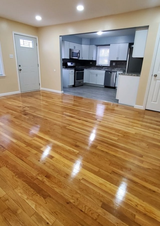 kitchen featuring sink, stainless steel appliances, light hardwood / wood-style floors, decorative backsplash, and white cabinets