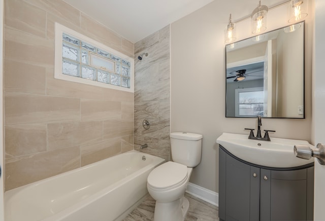 full bathroom featuring vanity, a healthy amount of sunlight, tiled shower / bath combo, and toilet