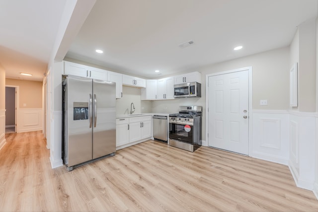 kitchen with white cabinets, appliances with stainless steel finishes, light wood-type flooring, and sink