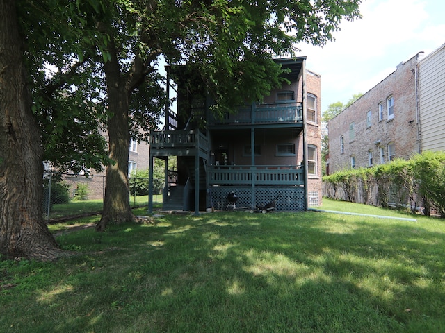 back of house featuring a lawn and a balcony