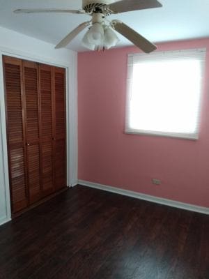 unfurnished bedroom with a closet, ceiling fan, and dark wood-type flooring