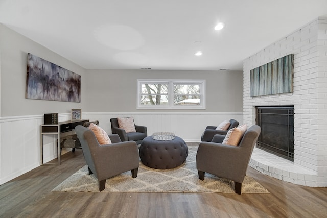 living room with hardwood / wood-style floors and a brick fireplace