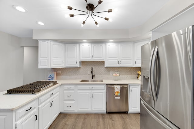 kitchen with white cabinets, appliances with stainless steel finishes, and light hardwood / wood-style flooring