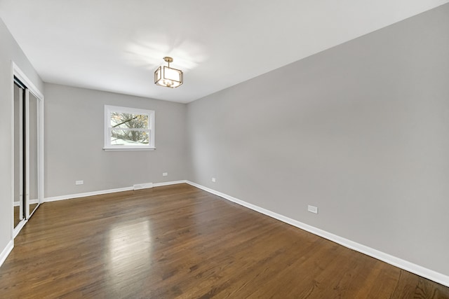 unfurnished room featuring dark hardwood / wood-style flooring and a chandelier